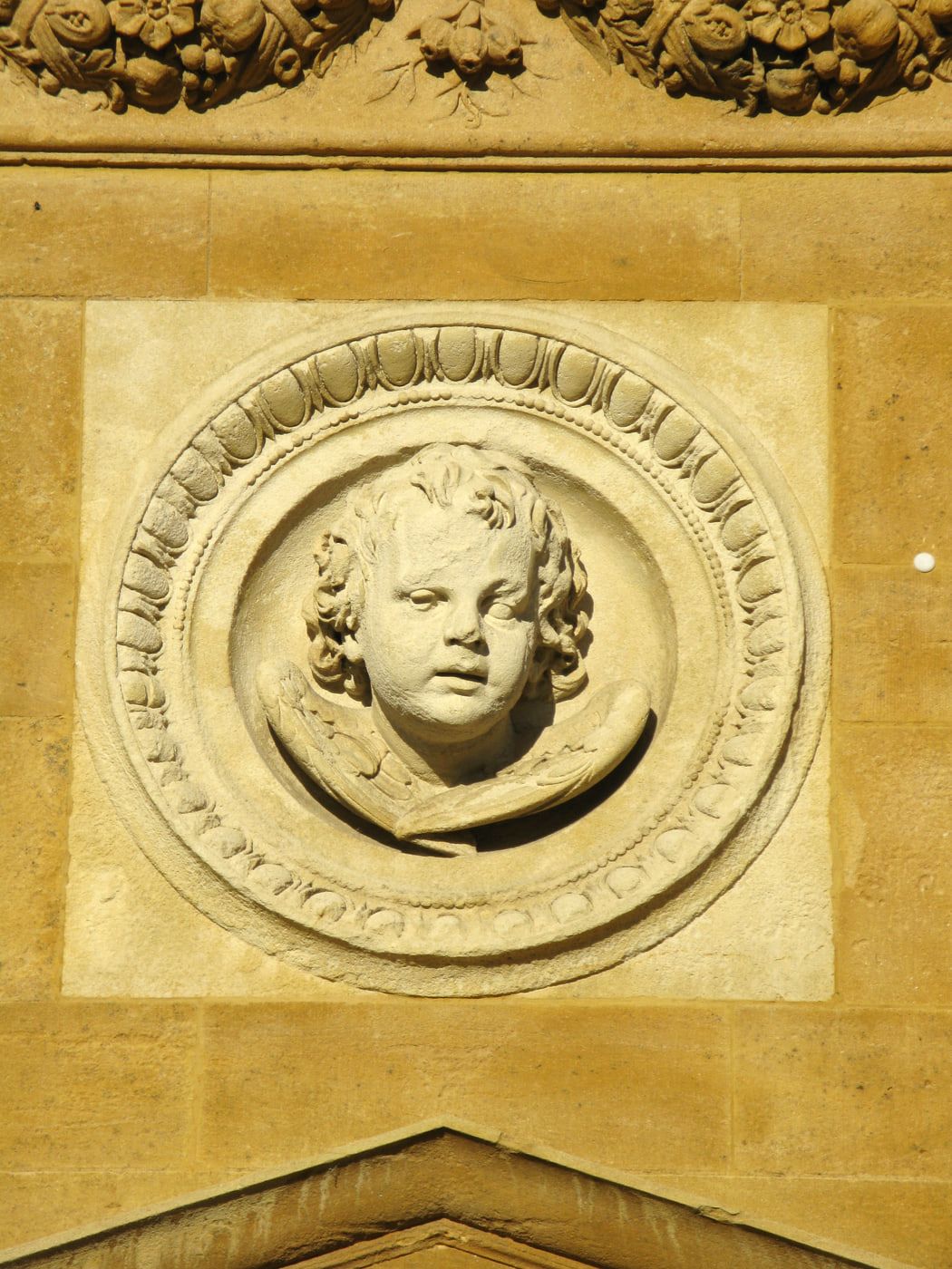 Rundrelief eines Puttenkopfs von Karl Friedrich Moest am äußeren Eingangsportal auf Hauptfriedhof Karlsruhe